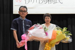県会計管理者への就任を祝って花束を贈呈された伊川秀樹氏（左）と、夫人の隆子さん＝９日、浦添市