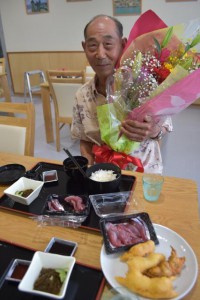 １番客の松川さんには花束か贈呈され、その後松川さんはおいしい刺し身を味わった＝15日、伊良部漁協の「おーばんまい食堂」