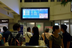 那覇空港滑走路の閉鎖に伴い離発着が大幅に遅れた。案内板で出発時間を確認する乗客ら＝17日、宮古空港