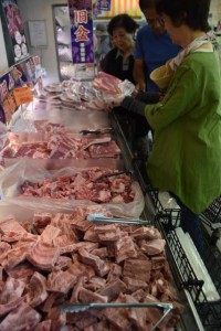 旧盆入りを前に豚のソーキ骨や三枚肉を買い求める客＝22日、市内の大型スーパー