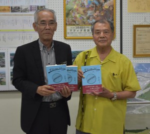 久貝さんが（右）が宮國教育長（左）に新書を手渡した＝21日、市教育委員会