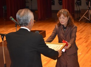 宮國教育長（手前）から狩俣婦人女性の会に表彰状が贈られた＝18日、市中央公民館