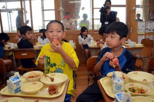 ハイビスカスのカップケーキをおいしそうに食べる児童たち＝25日、西辺小学校