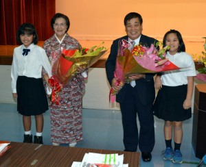 孫から花束の贈呈を受け笑顔を見せる新城元吉さん（中央右）と妻の悦子さん（同左）＝16日、城辺公民館