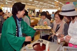 観光客にサヤインゲンの天ぷらを振る舞う専門部会のメンバーら。積極的にアピールした＝12日、あたらす市場