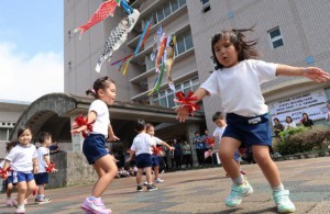 佐良浜保育所の園児たちが、掲揚したこいのぼりの下で元気に歌や踊りを披露した＝23日、県宮古合同庁舎