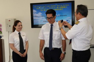 玉那覇社長（右）から襟章が訓練生の島袋さん（中央）と糸満さん（左）に贈呈された＝13日、下地島空港ＦＳＯパイロット訓練センター