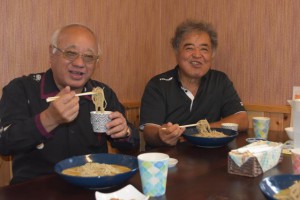 おいしいそばを食べて喜ぶ下地市長（左）と新里組合長（右）＝29日、上野新里のファーマーズキッチン「あらだてぃ」