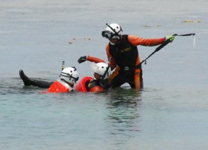 ロープで遊泳者を引き上げる海保の潜水士＝20日、城辺友利の博愛漁港