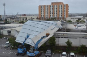 大型ショッピングセンターの一部店舗の屋根がめくれ上がり、応急処置で２台のショベルカーで屋根を押さえ付けた＝９日、宮古島徳洲会病院側から撮影