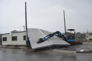 台風の暴風によって吹き飛ばされないよう重機で屋根を抑えていた＝９日、平良松原