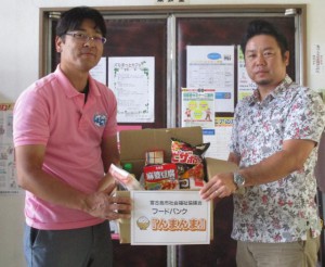 筒井営業部長（左）から漢那地域福祉課長へ食品が手渡された＝15日、市社会福祉協議会平良支所（提供写真）