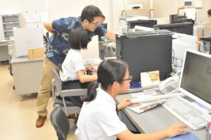 パソコンを使い本社社員から新聞を作る工程などを学ぶ下地さん（手前）と西村さん＝23日、宮古毎日新聞社