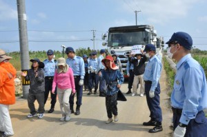 牛歩してトラックの進入を阻止する弾薬庫建設に反対する市民団体メンバー＝16日、保良鉱山周辺道路
