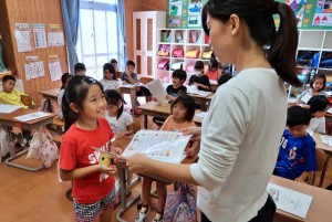 「よい子の歩み」を笑顔で受け取る児童たち＝25日、久松小学校