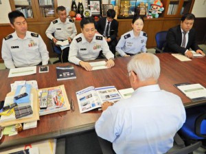 19年度版防衛白書の概要を説明する松永本部長（左から２人目）と関係者ら＝22日、市役所平良庁舎