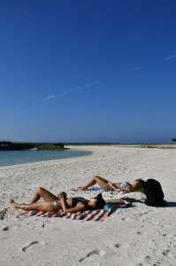 ビーチで横たわり肌を焼く女性ら＝24日、平良港トゥリバー地区のサンセットビーチ