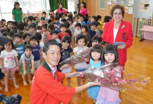 ＪＴＡの小堀支社長（手前左）らが桃の花を園児に贈った＝27日、あけぼの保育園