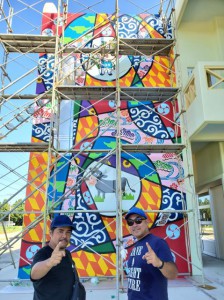 壁画が完成し記念撮影するアルベルト城間さん（左）と真栄里英樹さん＝４日、多良間塩川の観光拠点施設