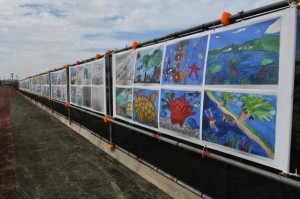 工事用フェンスに展示された子供たちの絵画＝22日、平良港トゥリバー地区