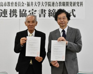 協定書を手にする宮國教育長（左）と柳澤研究科長＝17日、市役所城辺庁舎