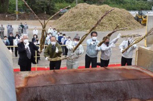 渡久山社長（左から３人目）らがサトウキビの束をベルトコンベアに投げ入れ操業が始まった＝１日、宮古製糖伊良部工場