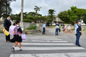 警察官と教職員が正門前に立ち、登校してくる子供たちを見守った＝７日、鏡原小学校前