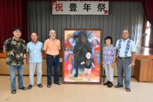 パーントゥの絵画を寄贈した大山さん（右から２人目）と作者の金城さん（中央）＝25日、パーントゥの里会館